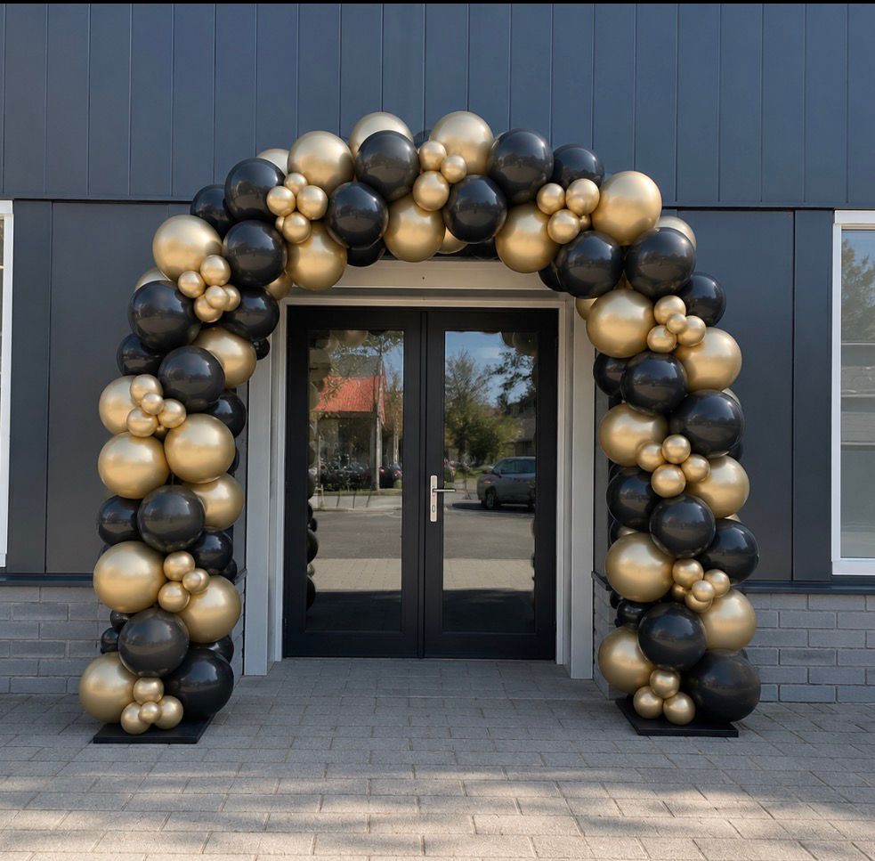 Ballonboog in zwart en goud rond de entree van een feestlocatie
